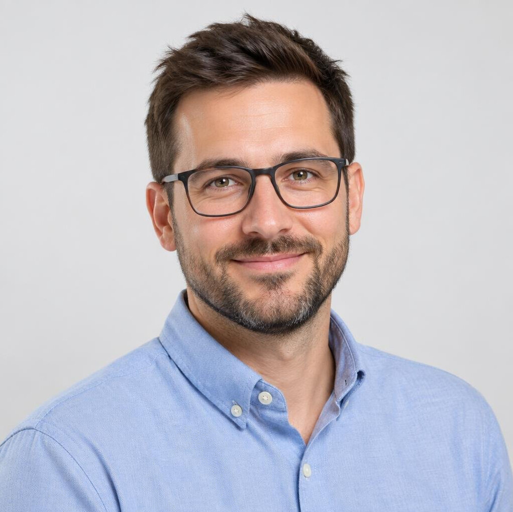 Studio portrait of a bearded man with glasses smiling