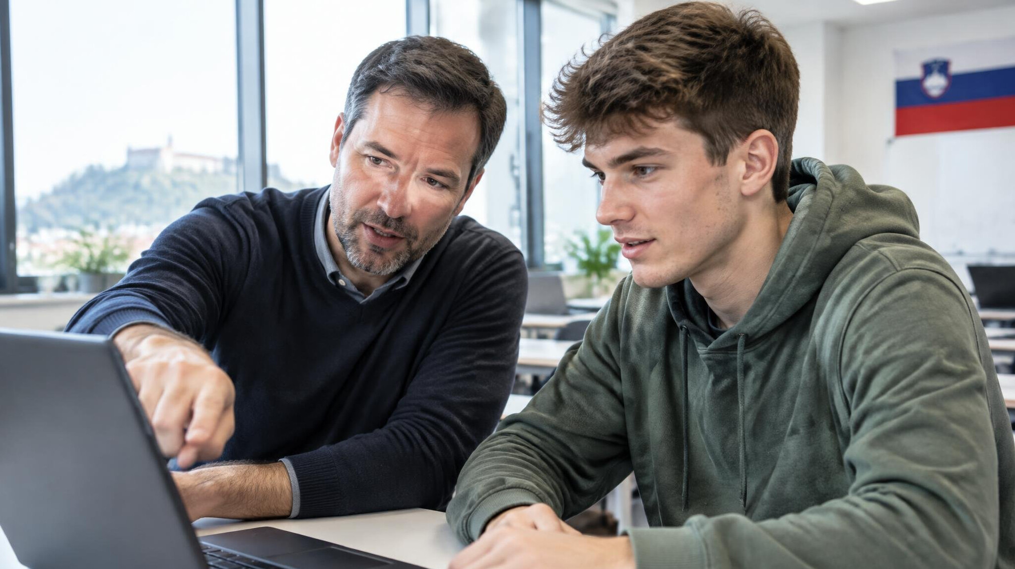 Mentor helping a student review code on a laptop